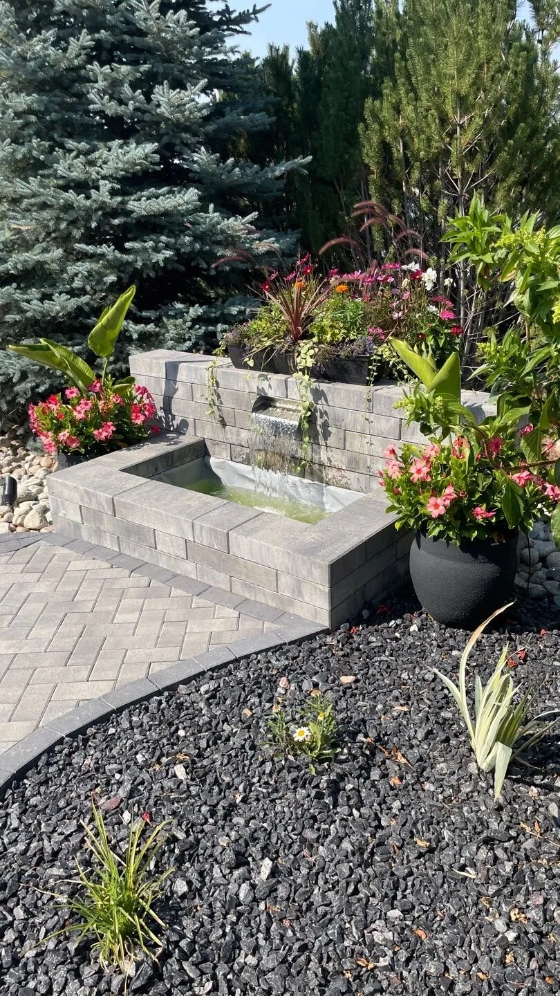 Stone water feature surrounded by flowering plants in a Colorado outdoor space
