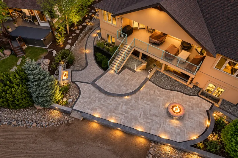 Aerial view of a paver patio, fire pit, and connected outdoor rooms