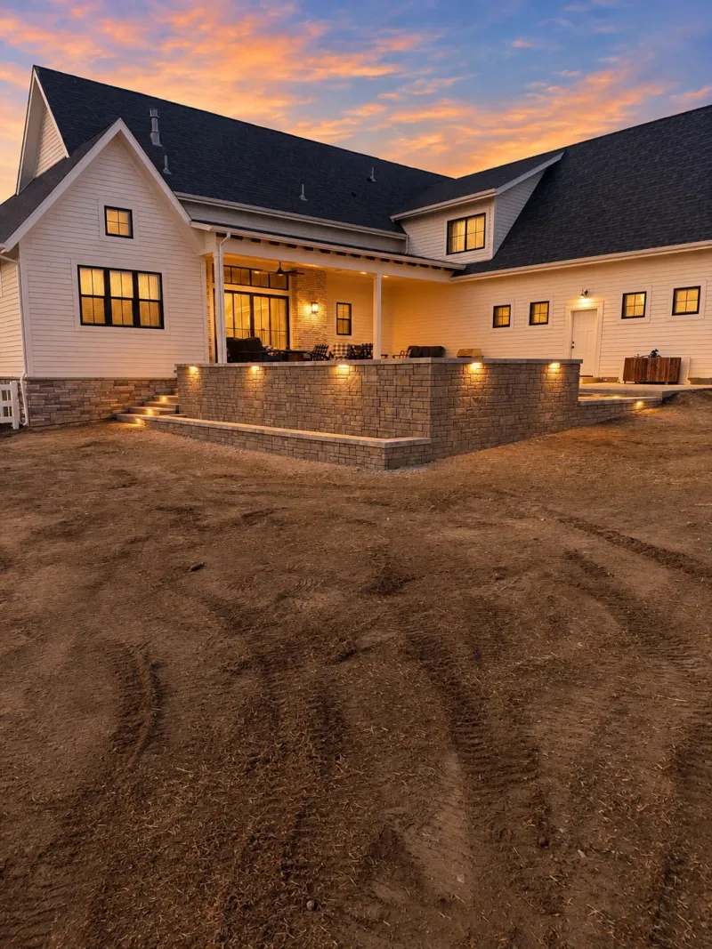 Illuminated stone wall supporting a covered outdoor patio